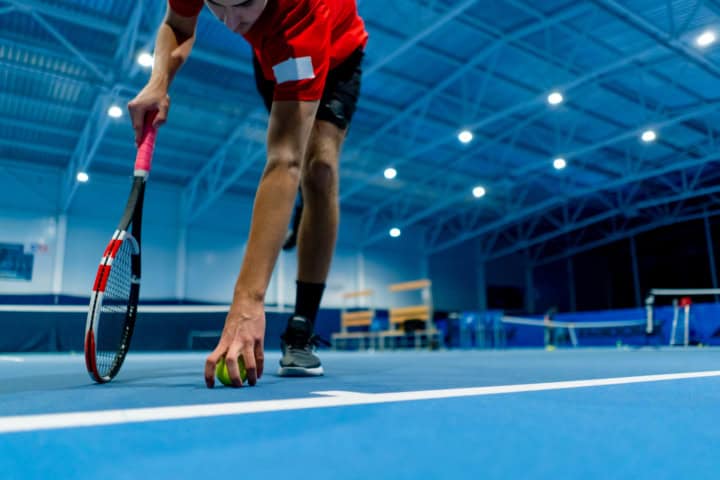 professional player coach standing in indoor tennis court in front background small ball big sport training